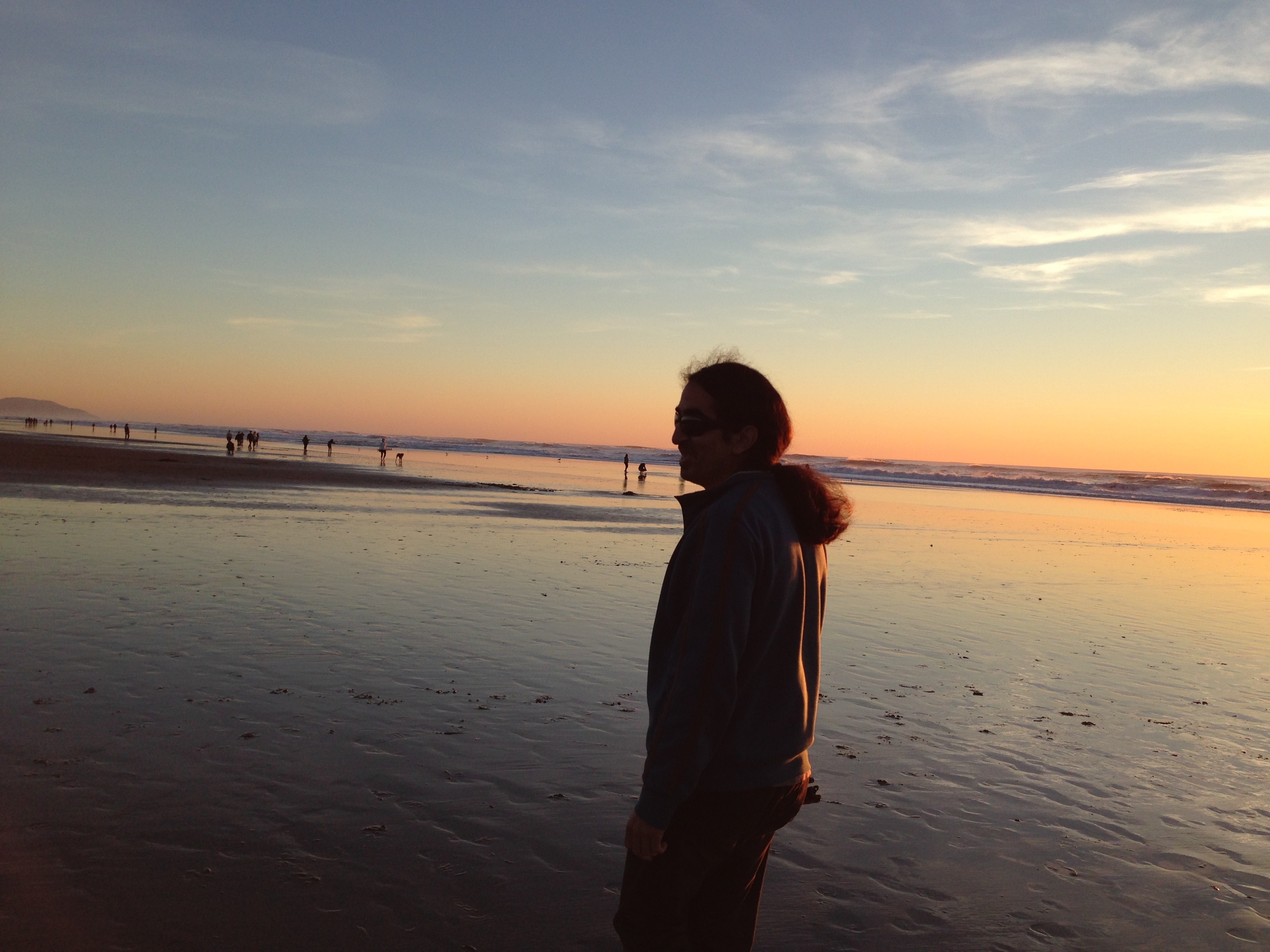 Ahmet is standing on the beach with sunset in the background